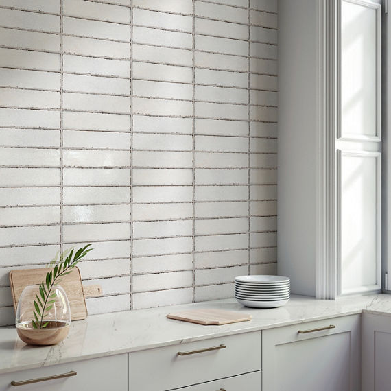 Kitchen with white metal look subway tile on backsplash, white cabinets, white countertop, and a wood cutting board on counter.