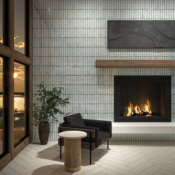 Living room with light blue metallic look subway tile on back wall, white rectangle floor tile in herringbone pattern, black sitting chair, and a lit fireplace.