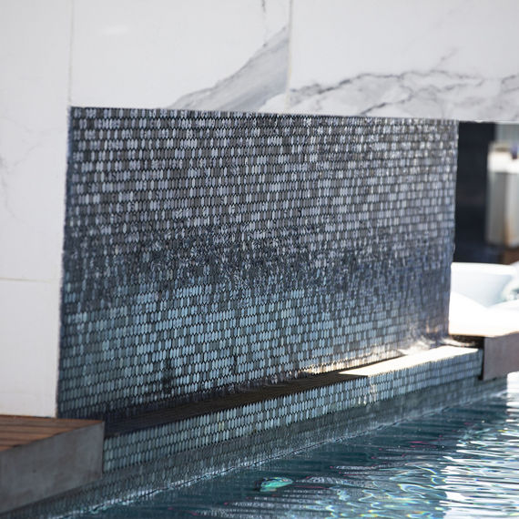 Inside of bridge over outdoor pool made of black glass hexagon mosaic tile and porcelain marble look slab on top of bridge.