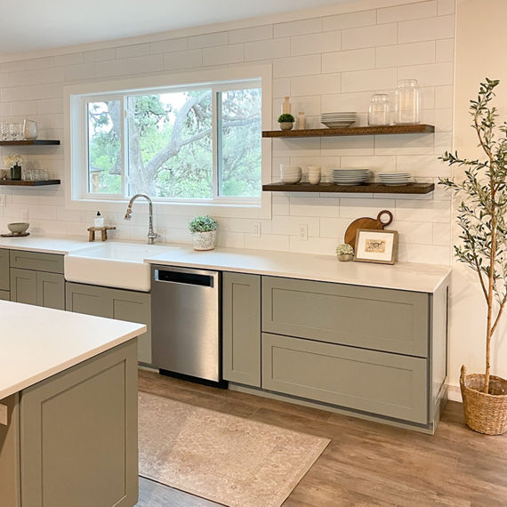 Kitchen with white subway tile on backsplash, white concrete look quartz countertops, and wood accents.