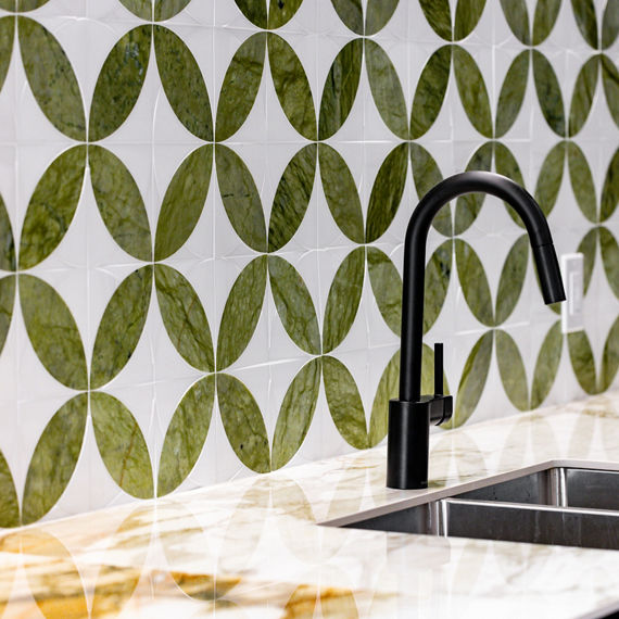 Lunch bar with white marble look porcelain slab counter on bar, black sink faucet, and greenery as accents.