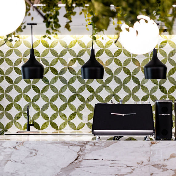 Lunch bar with white marble look porcelain slab counter on bar, black coffee station, and greenery as accents.