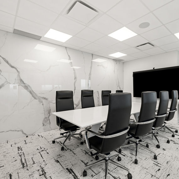 Work room with white marble look porcelain slab on back wall, black and white carpet, and large white table with black sitting chairs.
