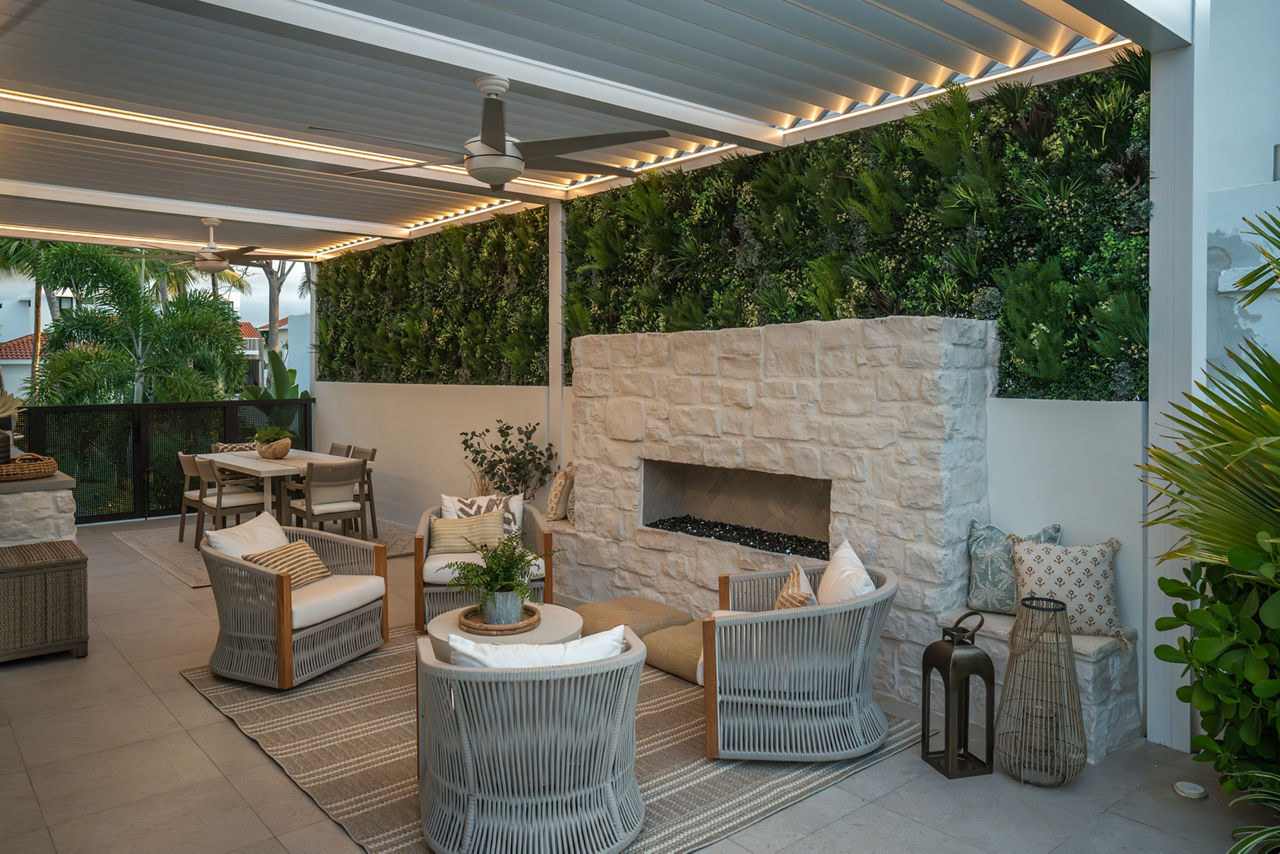 Backyard with white stone look pavers, beige chairs, and a white stone chimney.