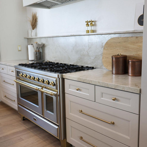 Kitchen with a beige quartzite slab on the backsplash and countertop, white cabinets, and wood floors.