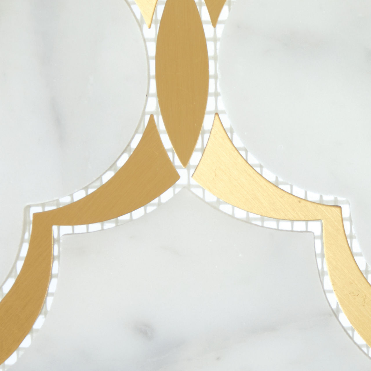 Abstract gold geometric shapes are inlaid into a smooth white marble background. The design features curved arcs forming a repeating ornamental pattern. Subtle gray veining in the marble adds texture and depth to the composition. The overall look is 