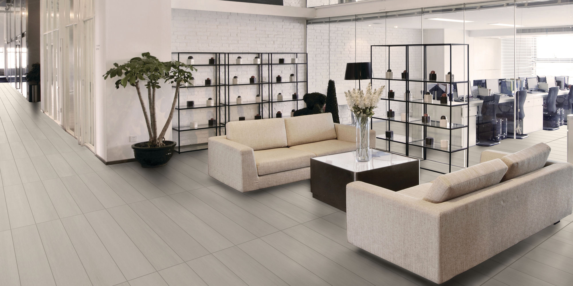 Office lobby with gray rectangle concrete look floor tile, white couches, and floor to ceiling windows.