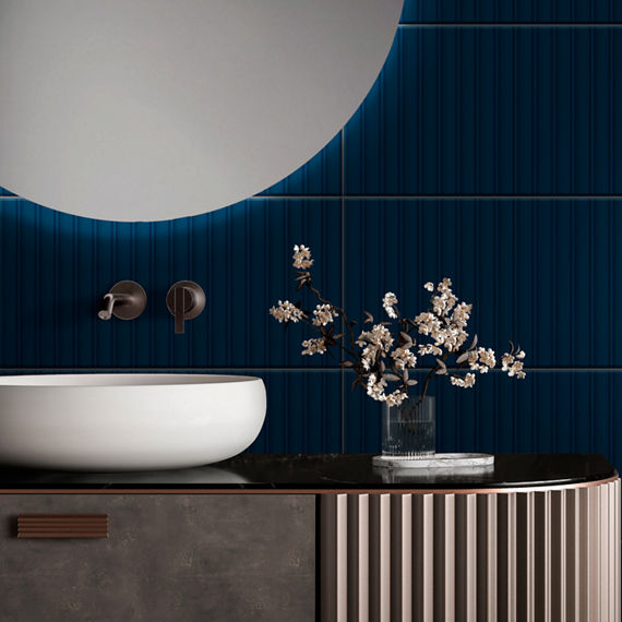 Bathroom sink with dark wooden art deco style counter, white sink, round mirror above sink, and a blue ridged rectangle tile on wall and backsplash.