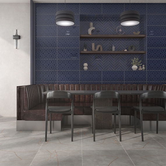Restaurant with blue rectangle wall tile with circle pattern on back wall, white walls, gray stone look square floor tile, brown booth, and black table with black chairs.