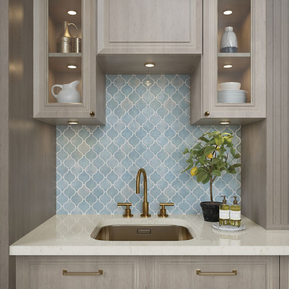 Kitchen with blue arabesque mosaic tile on backsplash, white countertop, and beige wood cabinets.