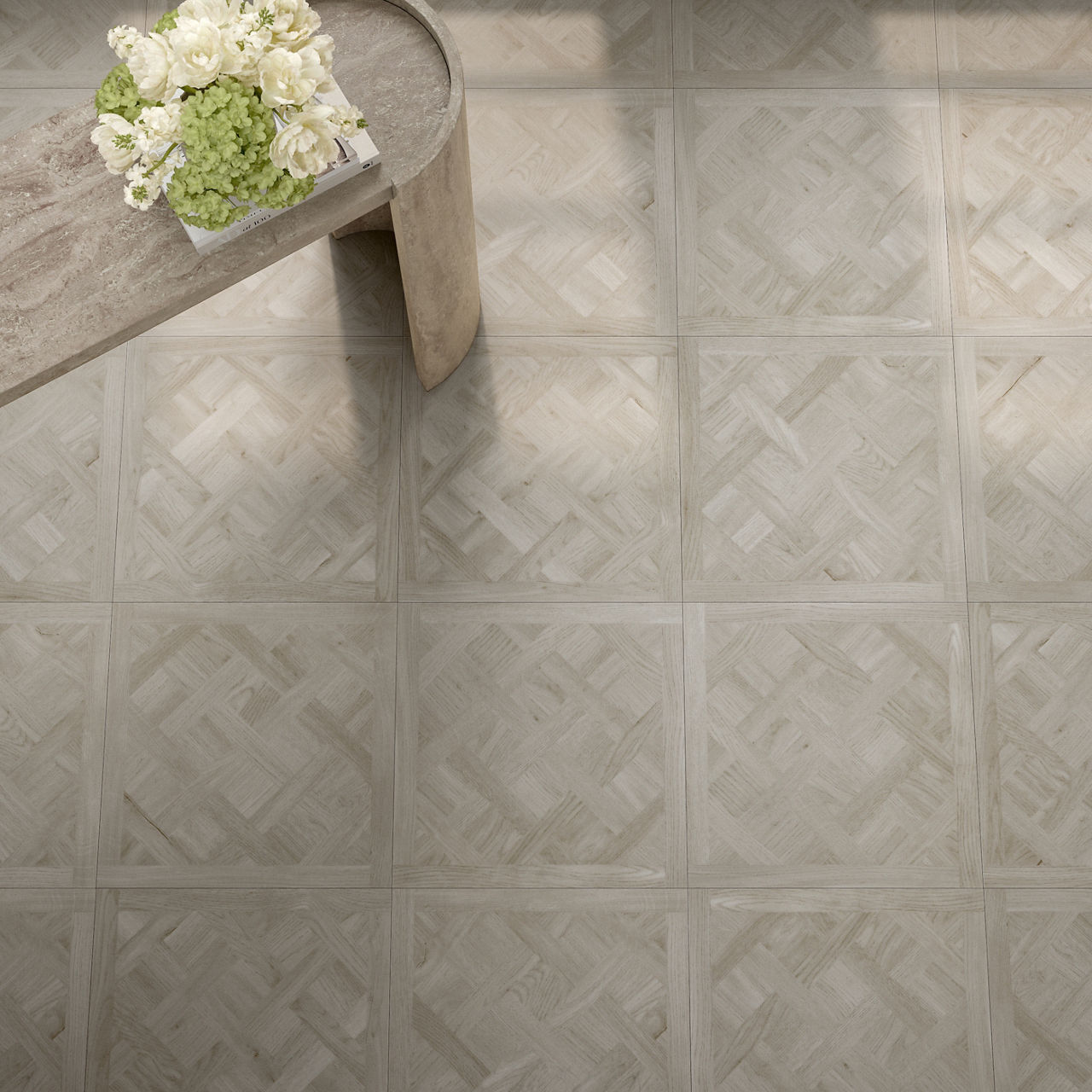 Overhead view of a light wood patterned tile floor with a wooden bench in the upper left corner topped with a white and green floral arrangement, set in a calm, minimal space with soft natural lighting and a neutral palette.