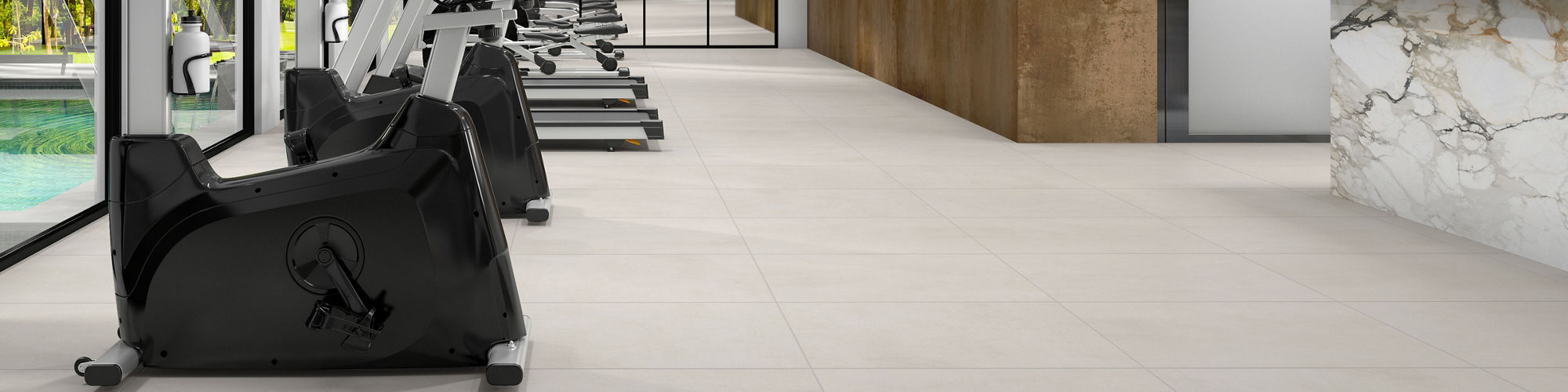 Indoor gym with light gray concrete look large rectangle floor tile, white side wall, metal look porcelain back wall, white marble look counter, and various exercise machines.