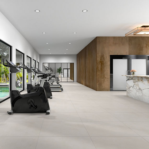 Indoor gym with light gray concrete look large rectangle floor tile, white side wall, metal look porcelain back wall, white marble look counter, and various exercise machines.