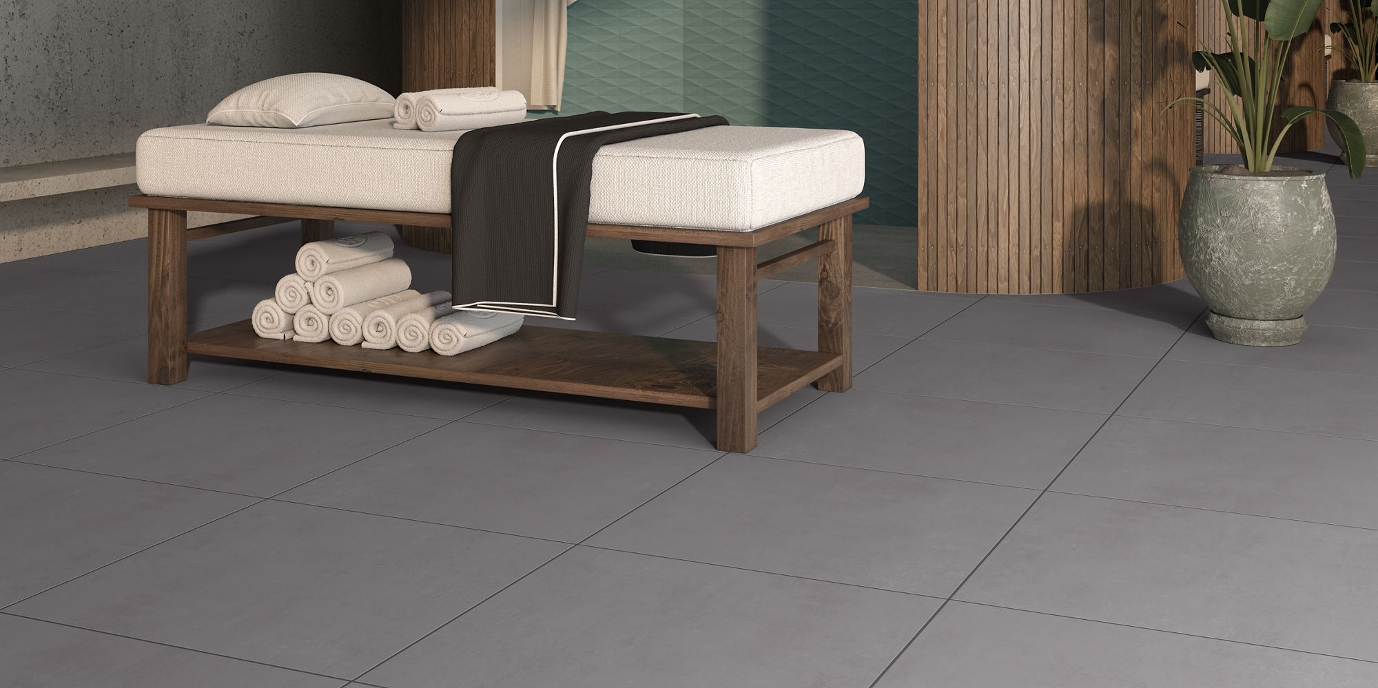 Spa room with gray square concrete look floor tile, shower with blue elongated hexagon mosaic on walls, and massage table in center.