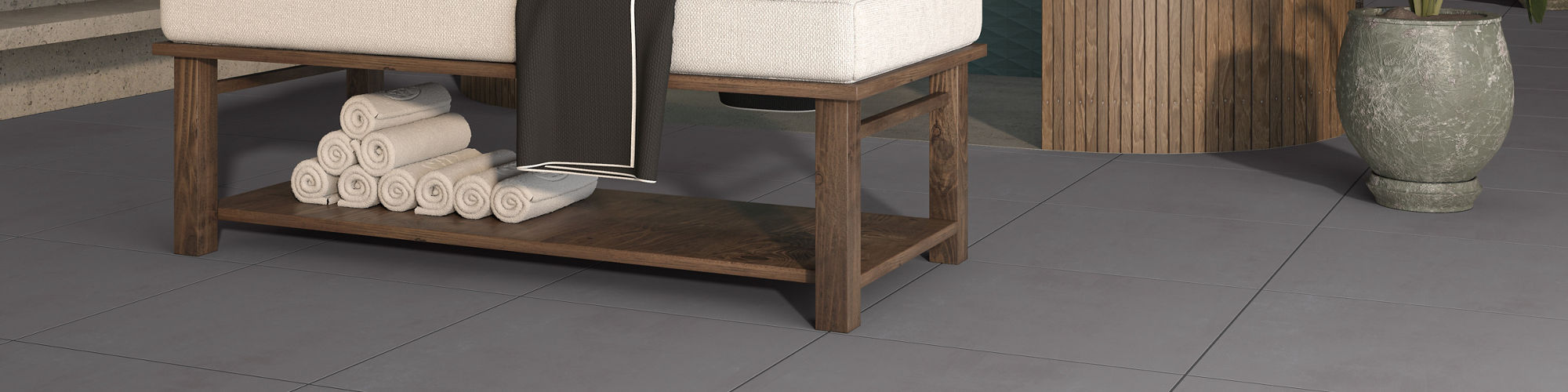 Spa room with gray square concrete look floor tile, shower with blue elongated hexagon mosaic on walls, and massage table in center.