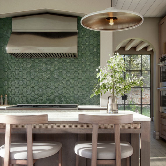 Kitchen with green hexagon wall tile on backsplash of stove area, white walls, center island, and wood cabinets and chairs.