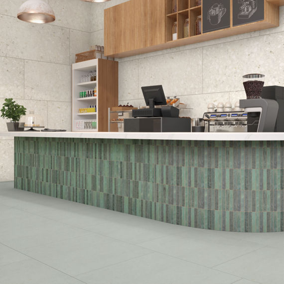 Coffee and pastry shop with white marble look quartz countertop, teal mosaic tile counter base, off white terrazzo look wall tile and gray floor tile.