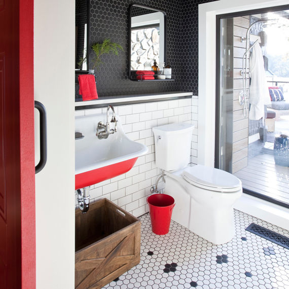 Bathroom with white hexagon mosaic and black hexagon mosaic tile on floor, black hexagon mosaic tile on top half of wall, white subway tile on bottom half of wall, and red accents.