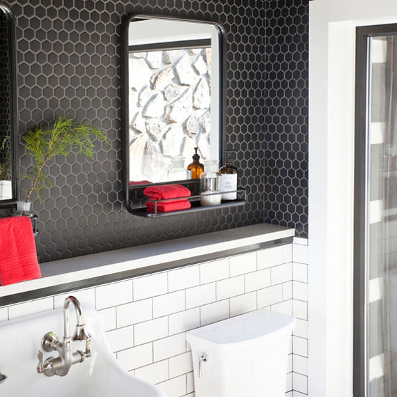 Close up of bathroom with white hexagon mosaic and black hexagon mosaic tile on floor, black hexagon mosaic tile on top half of wall, white subway tile on bottom half of wall, and red accents.