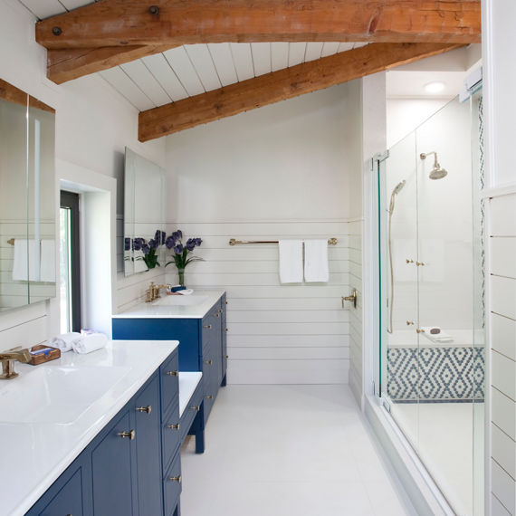Sideview of bathroom with blue cabinets on sink, white porcelain slab countertops, shower with diamond pattern on walls using white hexagon mosaic tile, and blue hexagon mosaic tile.