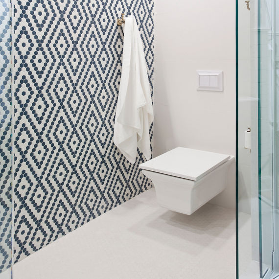 Floating toilet with diamond pattern on wall side wall using white hexagon mosaic tile and blue hexagon mosaic tile.