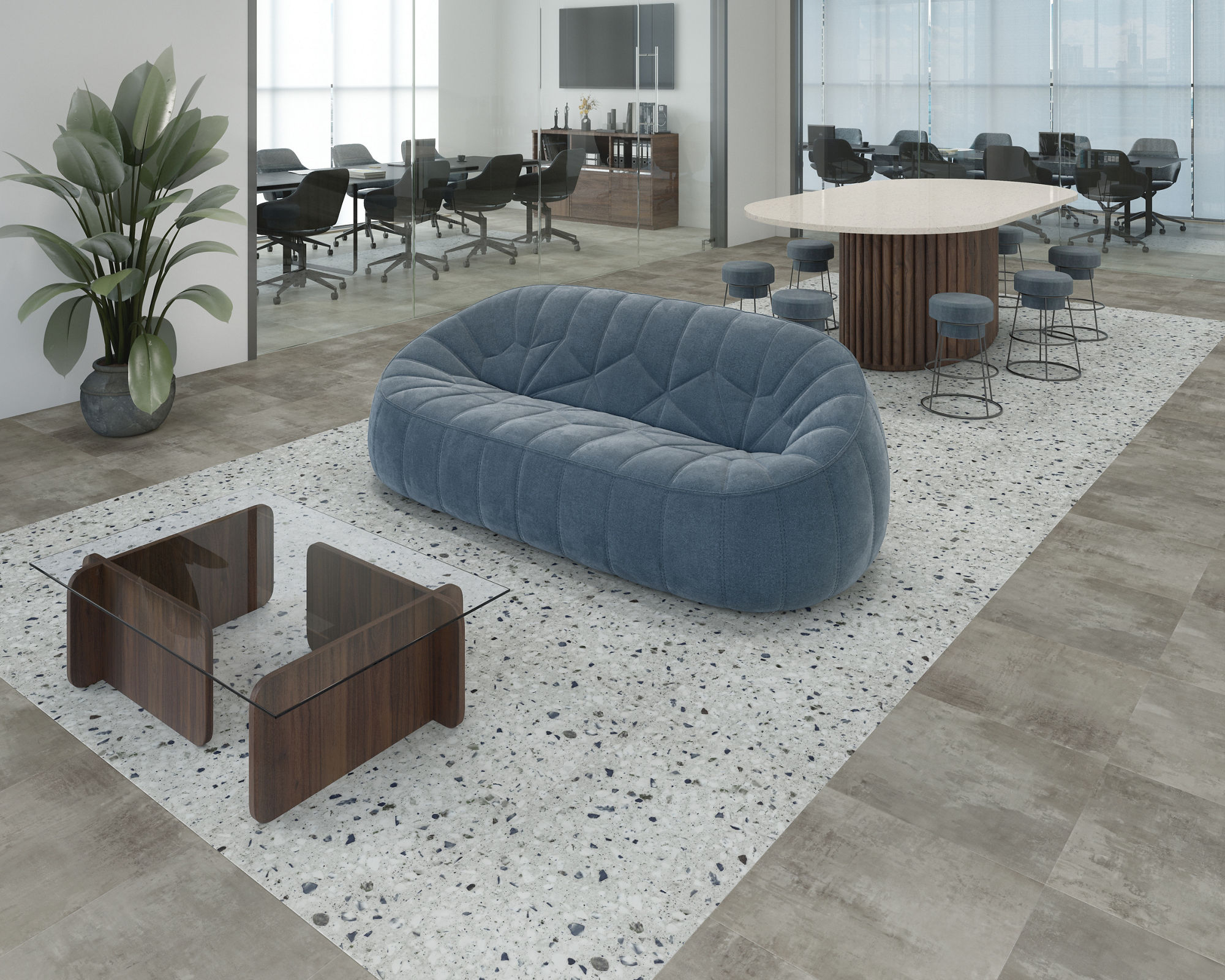 A contemporary office lounge features a plush blue sofa and two wooden side tables on a terrazzo rug. T