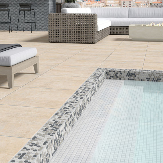 Pool side with white and gray penny round mosaic on pool lining, white square mosaic tile on pool floor, and beige square concrete look tile on backyard floor.