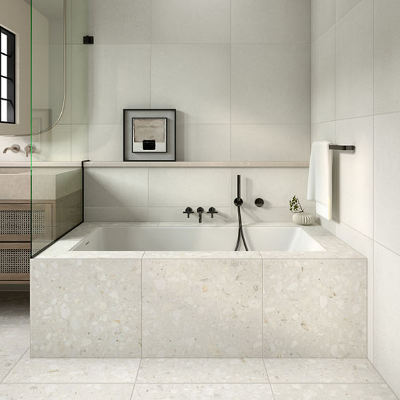 White bathroom with white terrazzo look tile on bathtub surround and floor.