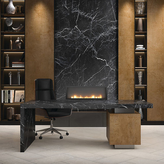 Home office with brass colored porcelain slab on back wall and desk, black marble look slab on back wall, and white rectangle floor tile in herringbone pattern.