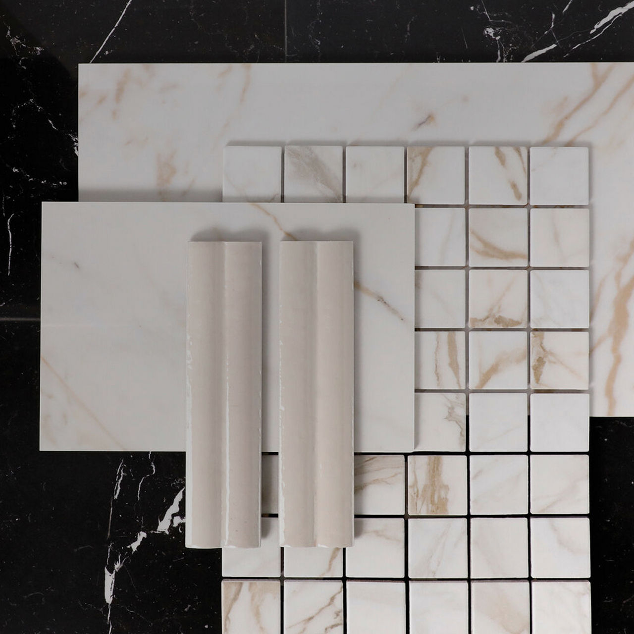 Assorted marble look tiles, mosaics, and trim pieces arranged in a coordinated flat lay.