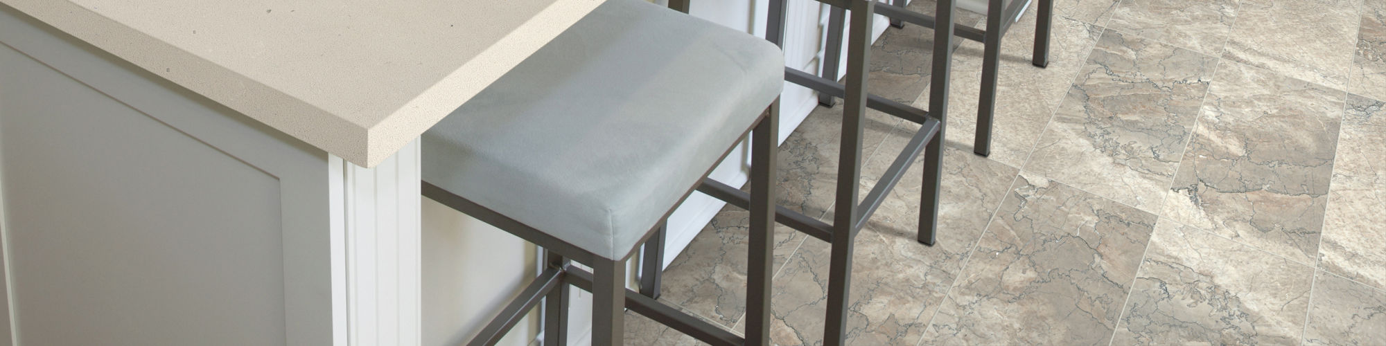 A contemporary kitchen features a large white island with a built-in sink and three cushioned stools.