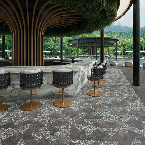 Outdoor bar with a gray pebble look mosaic on the floor, gray quartz bar counter, black chairs, and view of the jungle in the background.