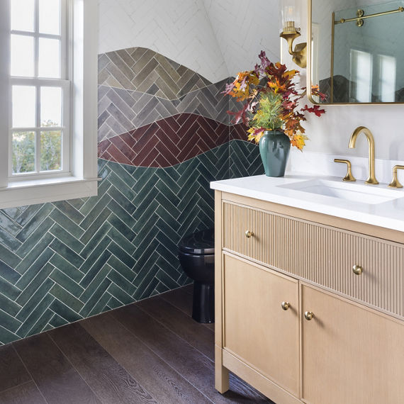 A contemporary bathroom features a striking herringbone tile wall in green, gray, and burgundy tones. 
