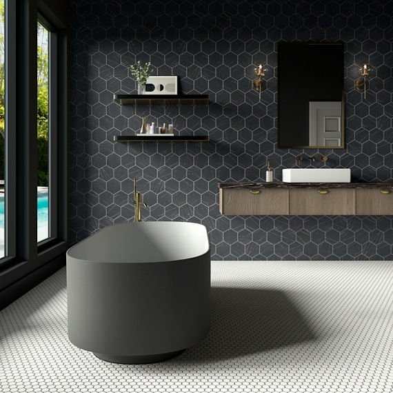 Bathroom with black marble look hexagon tile on back wall, white marble look hexagon mosaic, gray tub, wooden counter with black marble look countertop, and a white sink.