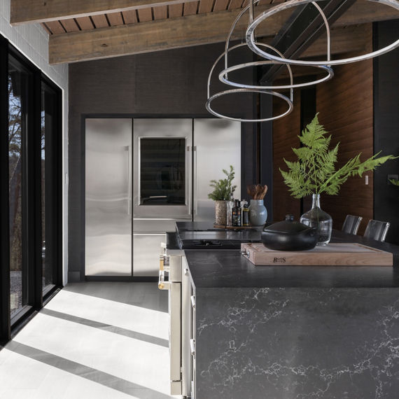 Chip Wades residential renovation, Pinhoti Peak, open kitchen and living room with closeup on marble look black quartz island and stainless steel refrigerator in the background.