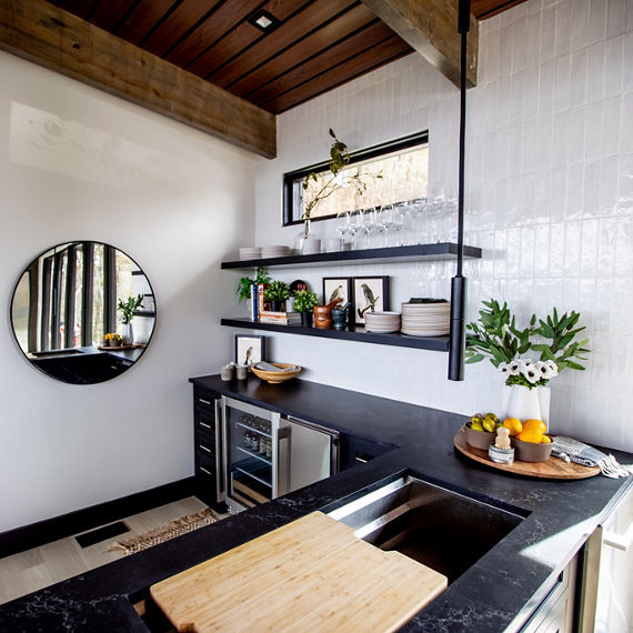 Chip Wades residential renovation, Pinhoti Peak, open kitchen with marble look black quartz countertop, white glossy tile backsplash, and floating shelves.
