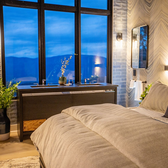 Chip Wades residential renovation, Pinhoti Peak, master bedroom with black quartz vanity countertop, gray glossy wall tile, and bed with tan tufted headboard.