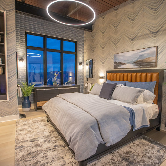 Chip Wades residential renovation, Pinhoti Peak, master bedroom with black quartz vanity countertop, gray glossy wall tile, and bed with tan tufted headboard.