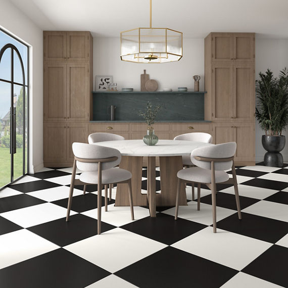 Dining room with black and white square concrete look tile in checkered pattern, wood cabinets, and white dining table with white chairs.