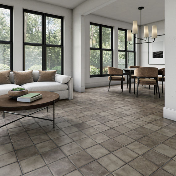 Living room with gray square concrete look floor tile, white couch, black dining table, and wood accents.