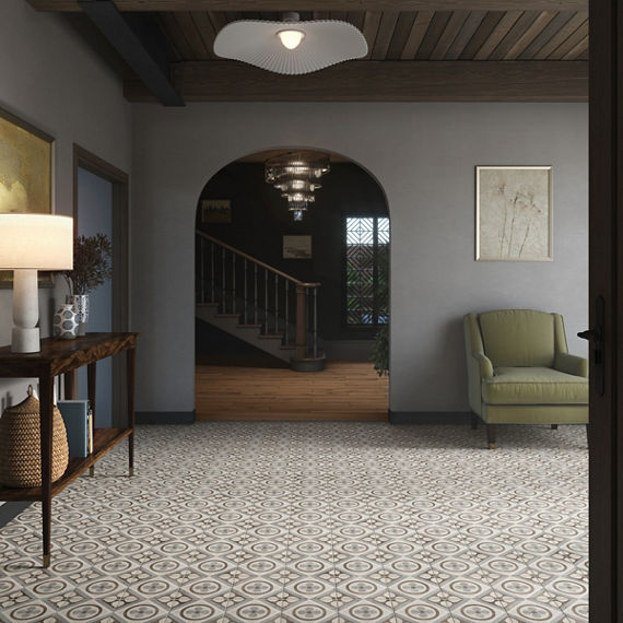 Entryway with white encaustic square floor tile, gray walls, arch showing hallway staircase, and a green chair to the side.