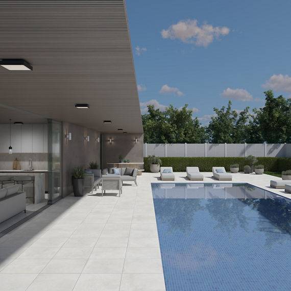 Backyard with white stone look pavers, white pool chairs, and a large pool.