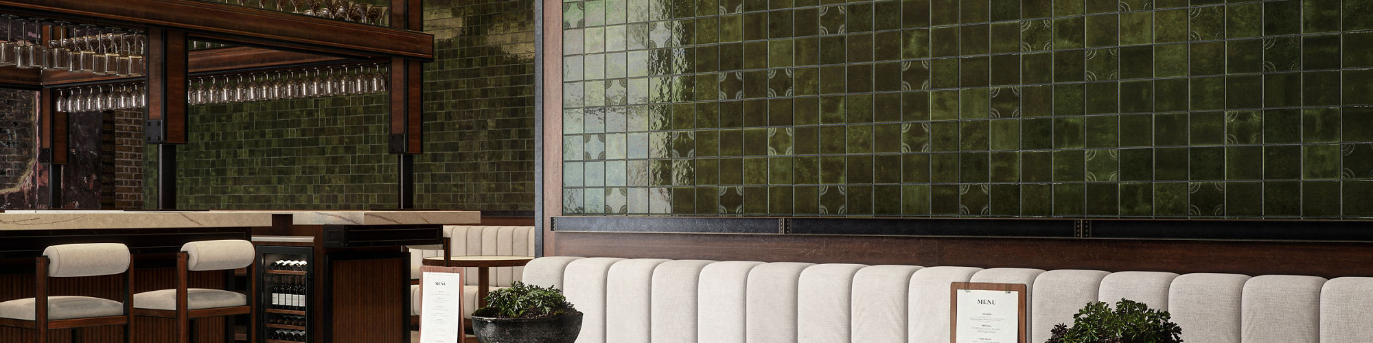 A contemporary lounge bar features plush seating, round tables, and a striking green tiled accent wall.