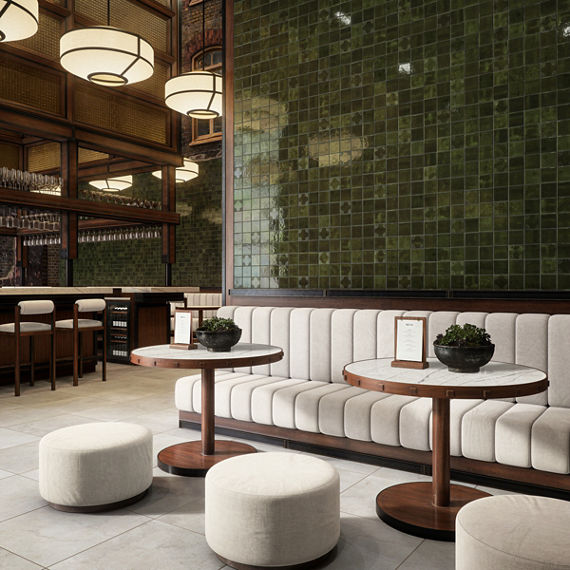 A contemporary lounge bar features plush seating, round tables, and a striking green tiled accent wall.