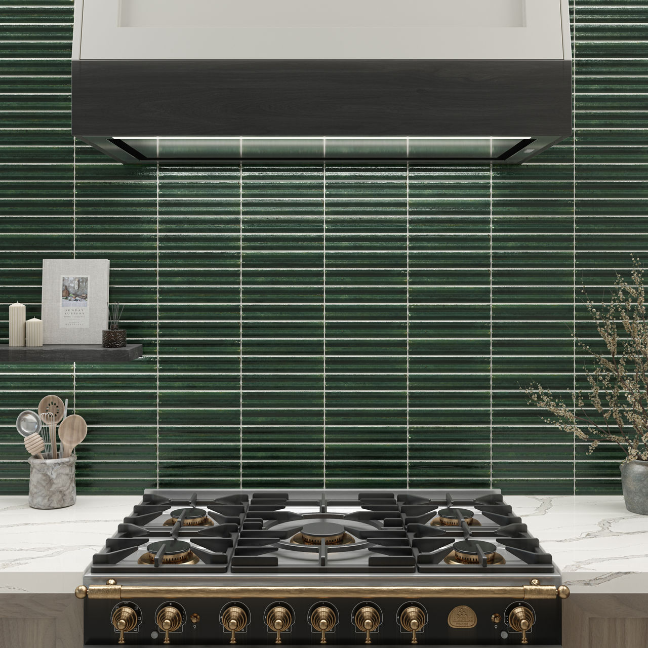 A modern kitchen with green fluted 2x10 tile backsplash, black and gold gas range beneath a sleek hood, marble countertop, and neatly arranged utensils.