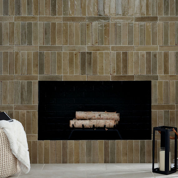 Fireplace with logs inside, white concrete look rectangle floor tile, and light brown subway tile surrounding fire place.