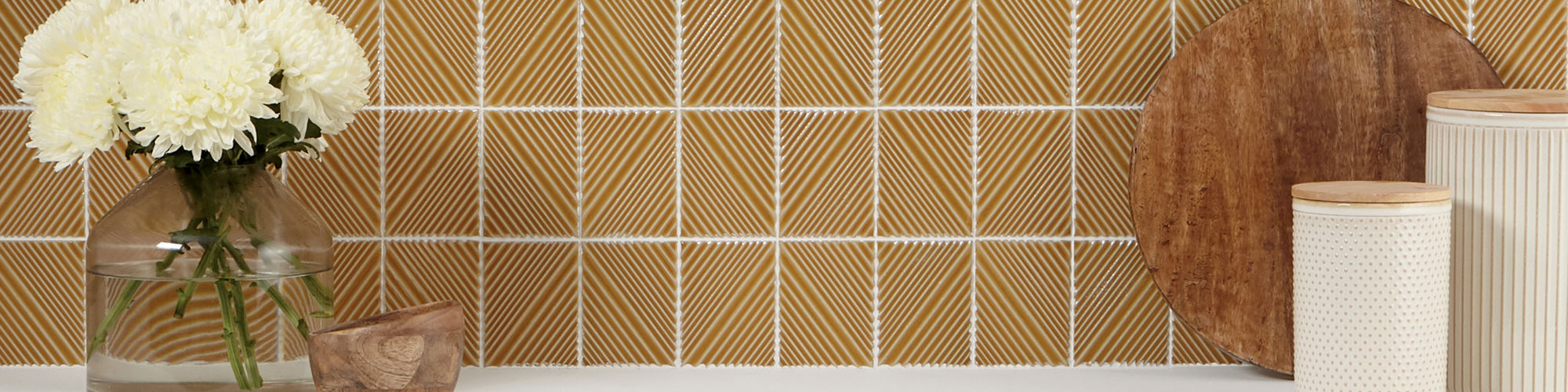 Kitchen with white cabinets, white countertop, and a yellow rectangle mosaic tile with 3d pattern on backsplash.