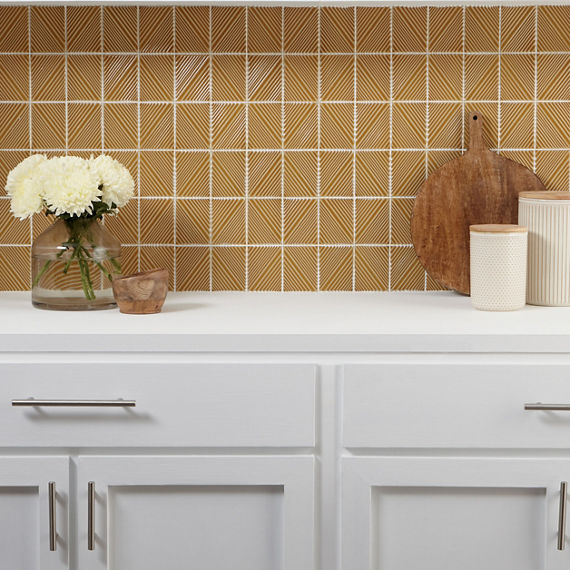 Kitchen with white cabinets, white countertop, and a yellow rectangle mosaic tile with 3d pattern on backsplash.