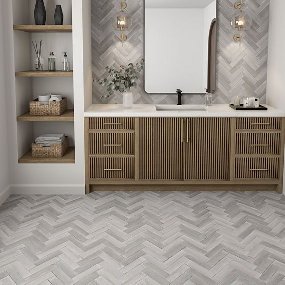 Bathroom with gray rectangle tile in herringbone pattern on back wall and floor, white countertop, and wood cabinets.