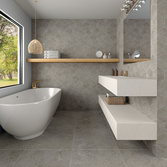 Bathroom with white countertop, white bathtub, gray hexagon concrete look tile on walls, gray concrete look rectangle tile on floor, and wooden accents.